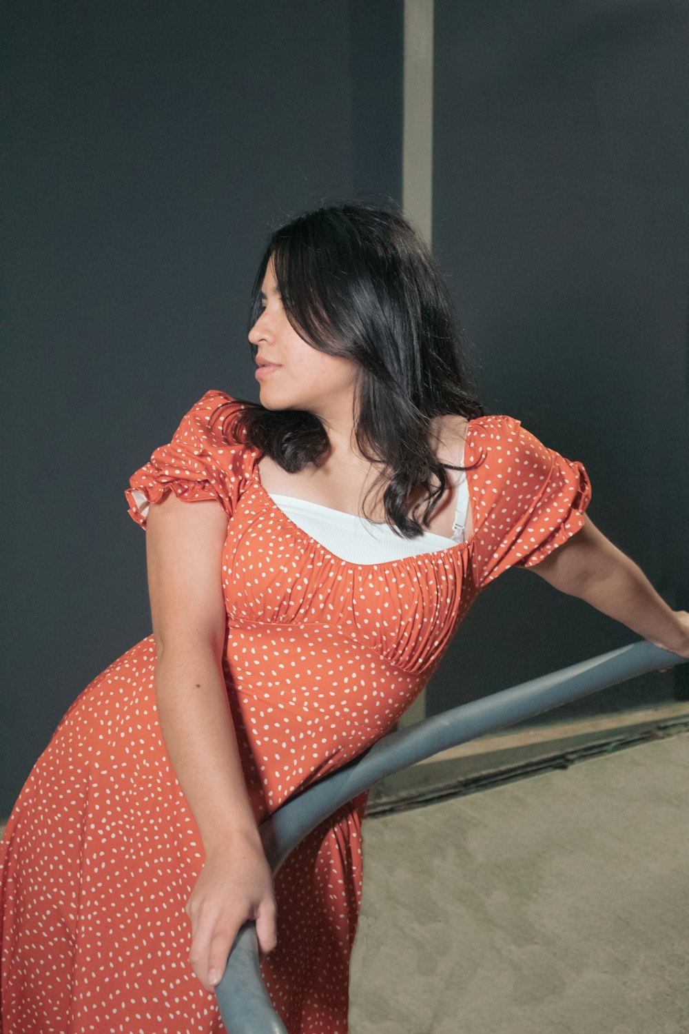 a woman in a polka dot dress leaning on a rail