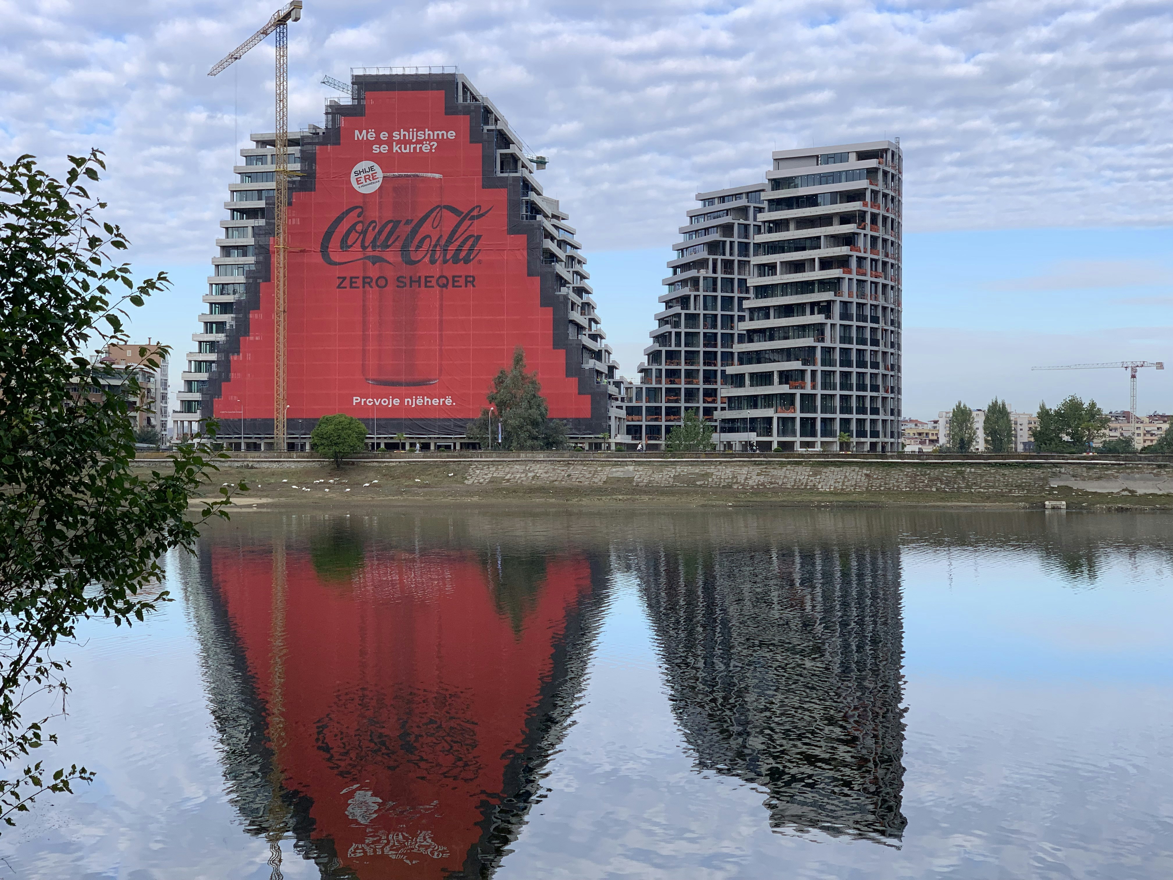 a large coca - cola advertisement is reflected in a body of water, Reflections
