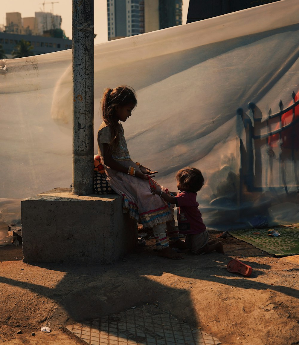 a woman and a child sitting on a cement block