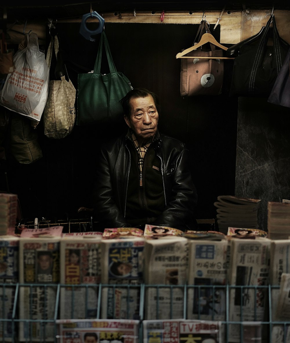 a man sitting in front of a table filled with newspapers