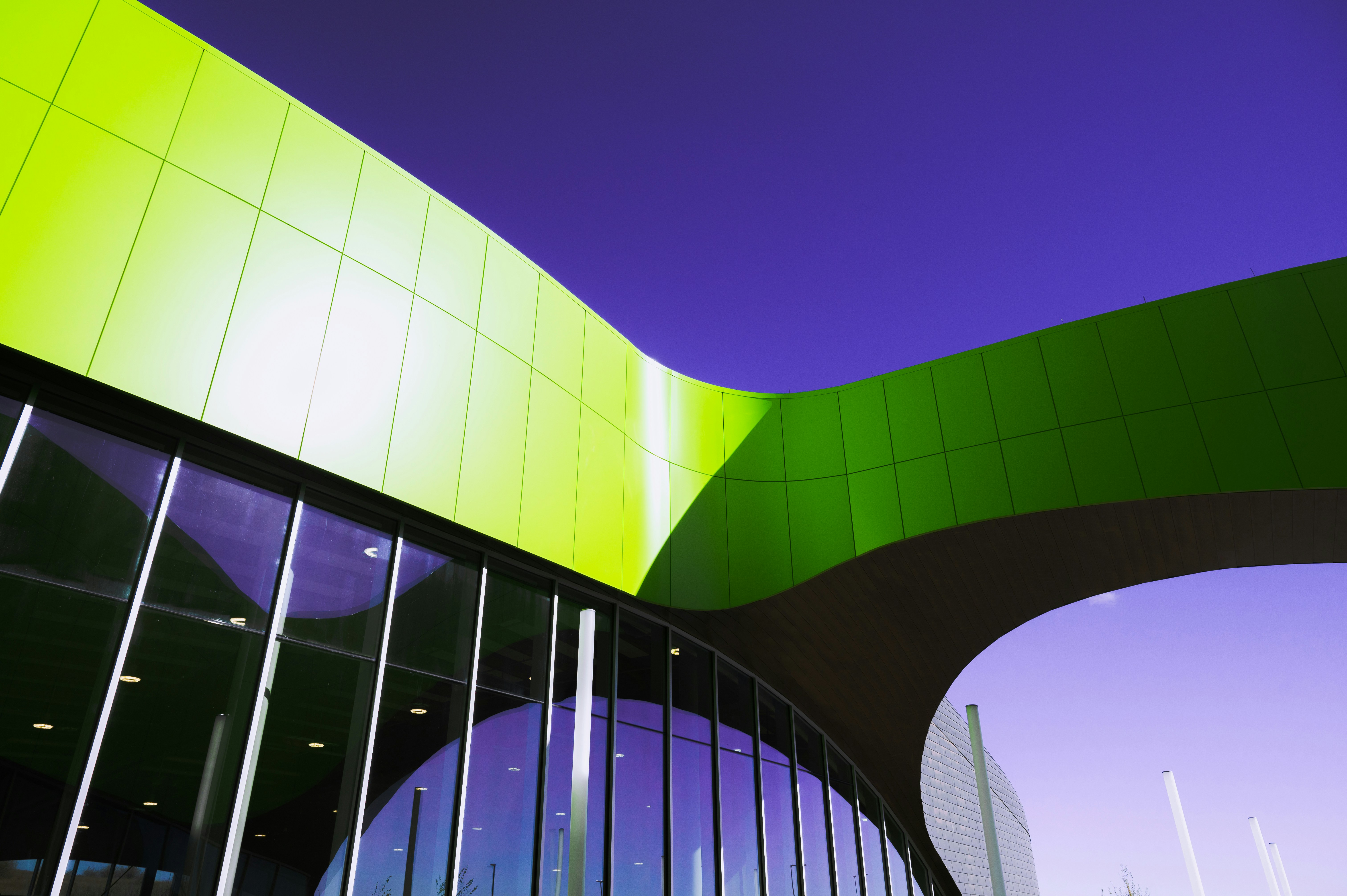Un edificio verde y púrpura con un puente sobre él