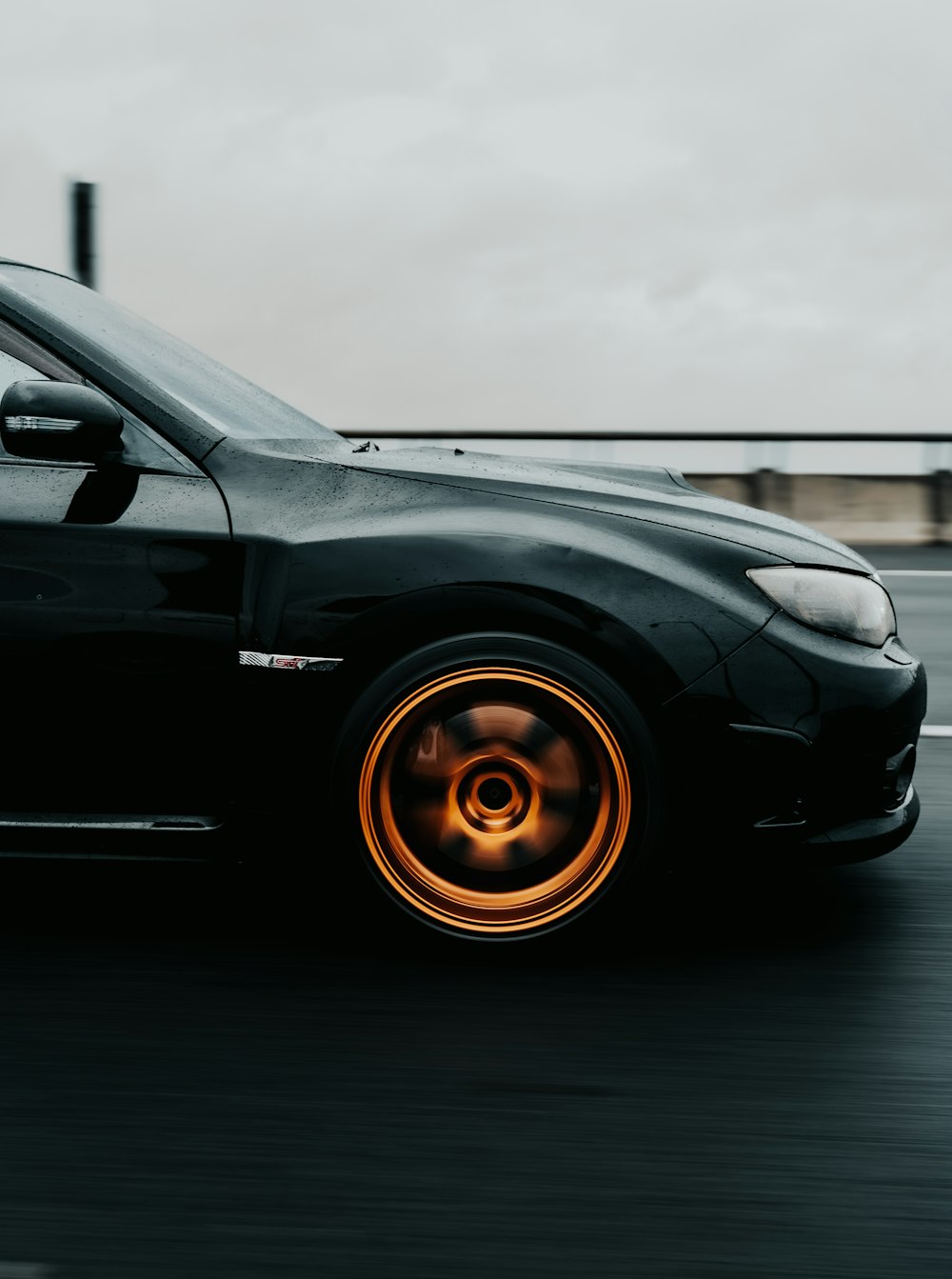 a black car driving down a street next to a bridge