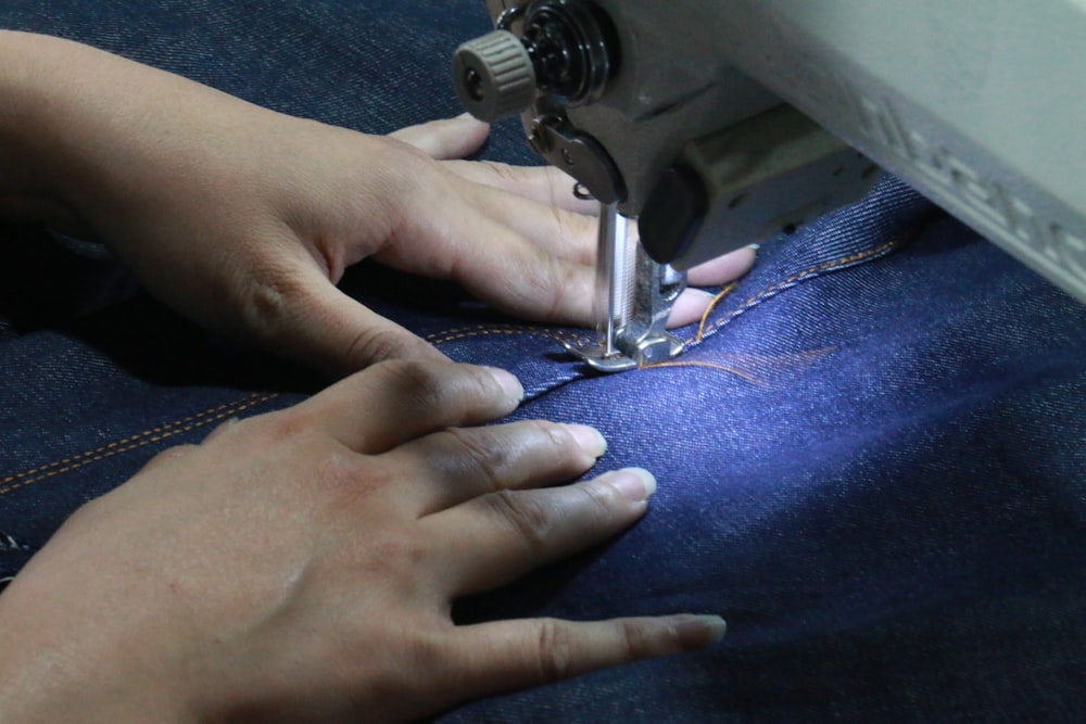 a woman using a sewing machine to sew jeans