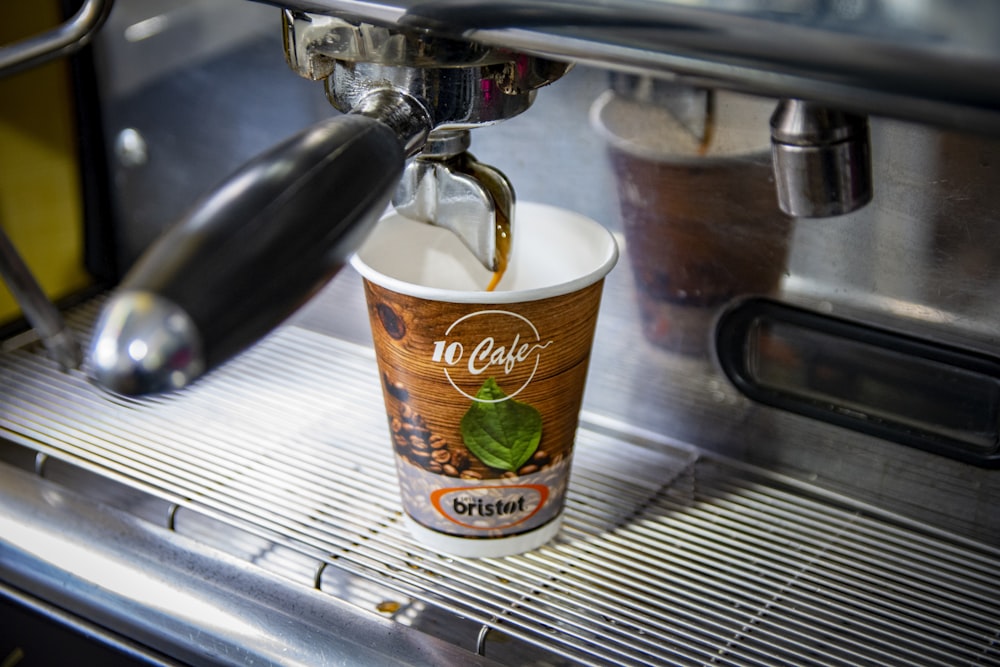 a cup of coffee being poured into a coffee machine