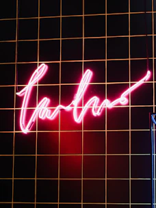 Sleek storefront sign glowing with magenta and gold accents against a charcoal background.