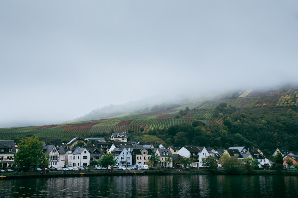 a town on the side of a river with a hill in the background