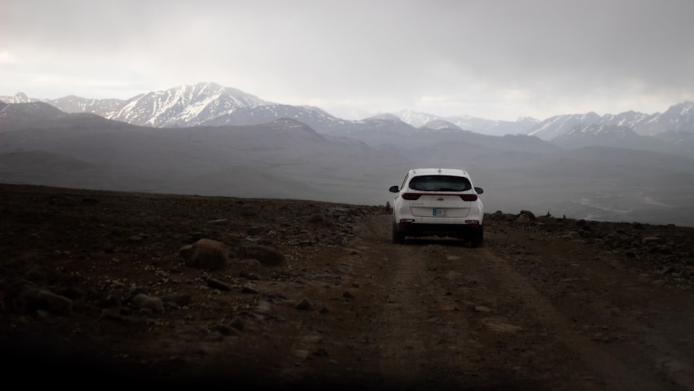 a white car driving down a dirt road