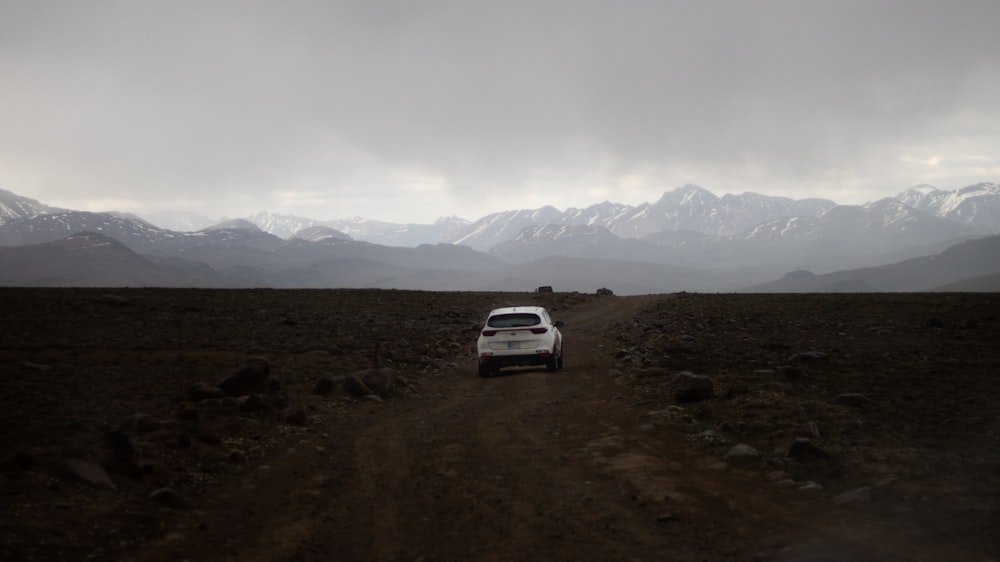 a white car driving down a dirt road