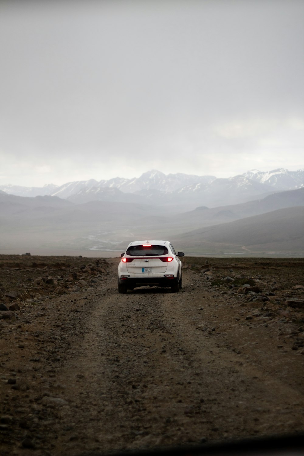 a white car driving down a dirt road