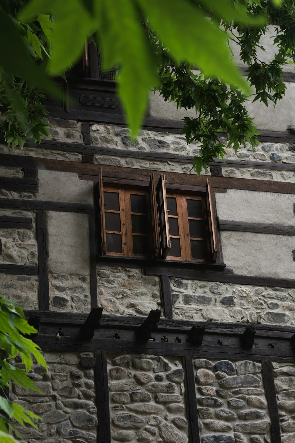 um edifício de pedra com duas janelas e persianas