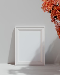 a white picture frame sitting next to a vase of flowers