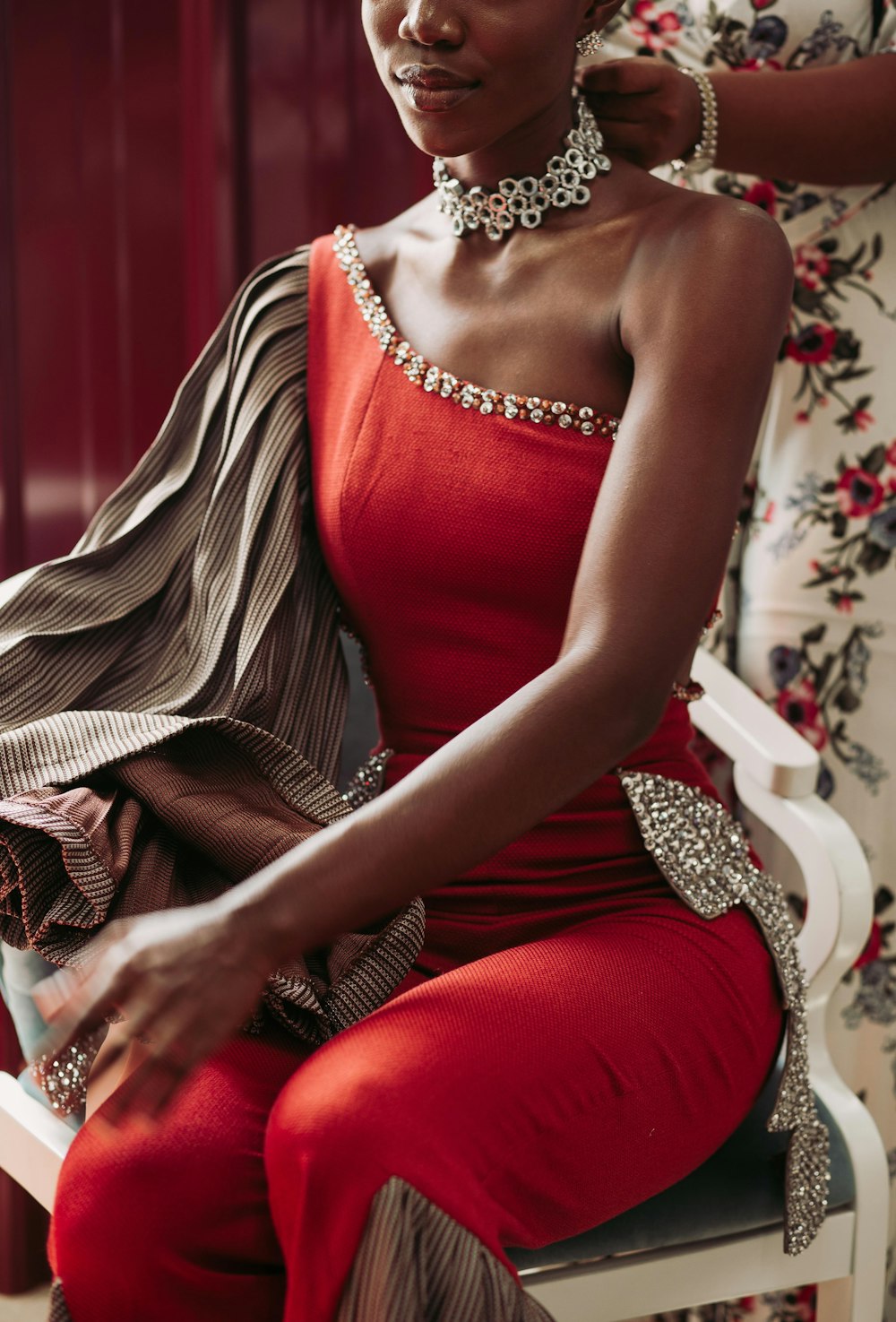 a woman in a red dress sitting on a chair