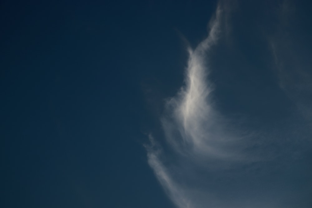 a plane flying in the sky with a cloud in the background