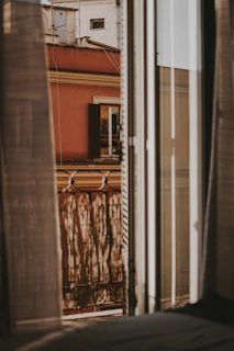 A quiet window with warm terracotta curtains filtering the afternoon sun.