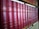 A row of classic books with red leather covers and gold lettering is neatly organized on a wooden bookshelf. The titles and authors' names appear embossed on the spines, suggesting a collection of literary works.