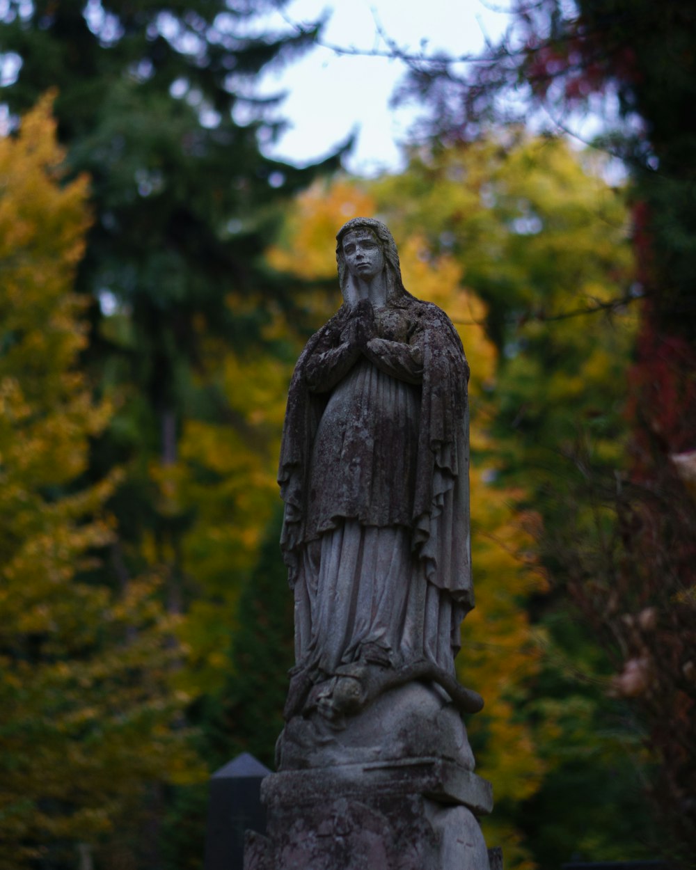 a statue of a woman standing in a cemetery