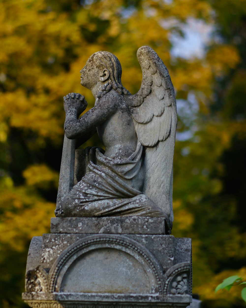 uma estátua de um anjo sentado em cima de uma sepultura