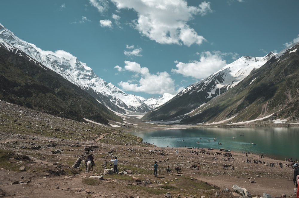 a group of people standing on top of a mountain next to a lake