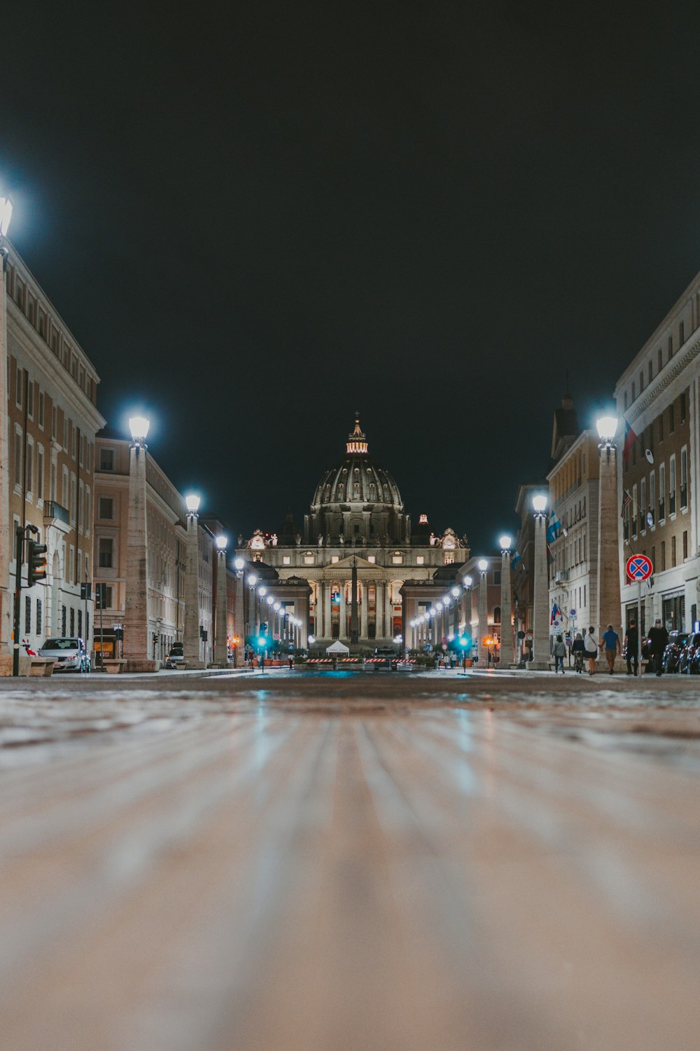 Eine Stadtstraße bei Nacht mit einem Kuppelgebäude im Hintergrund