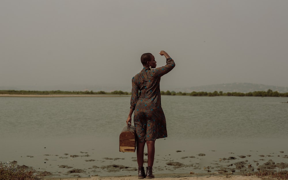 uma pessoa em pé em uma praia com uma mala