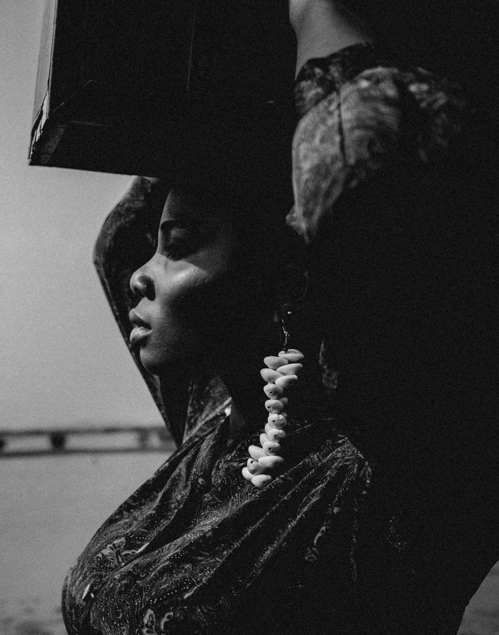 a black and white photo of a woman carrying a box