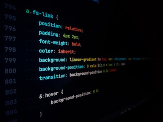 A close-up view of a computer screen displaying lines of CSS code, featuring style rules with properties like position, padding, font-weight, color, and background. The text appears in multiple colors including blue, red, green, and yellow on a black background.