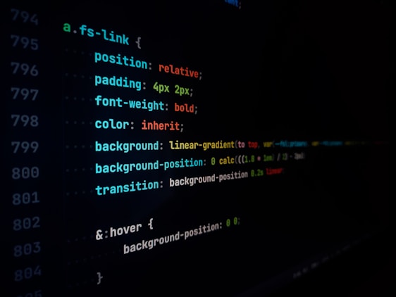 A close-up view of a computer screen displaying lines of CSS code, featuring style rules with properties like position, padding, font-weight, color, and background. The text appears in multiple colors including blue, red, green, and yellow on a black background.