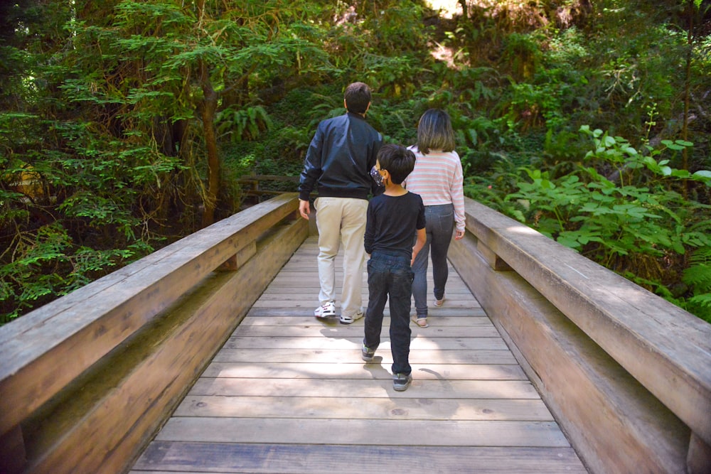 a family walking across a wooden bridge in the woods