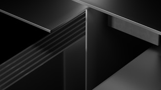Abstract 3D geometric shapes layered with high contrast lighting in black and gray.