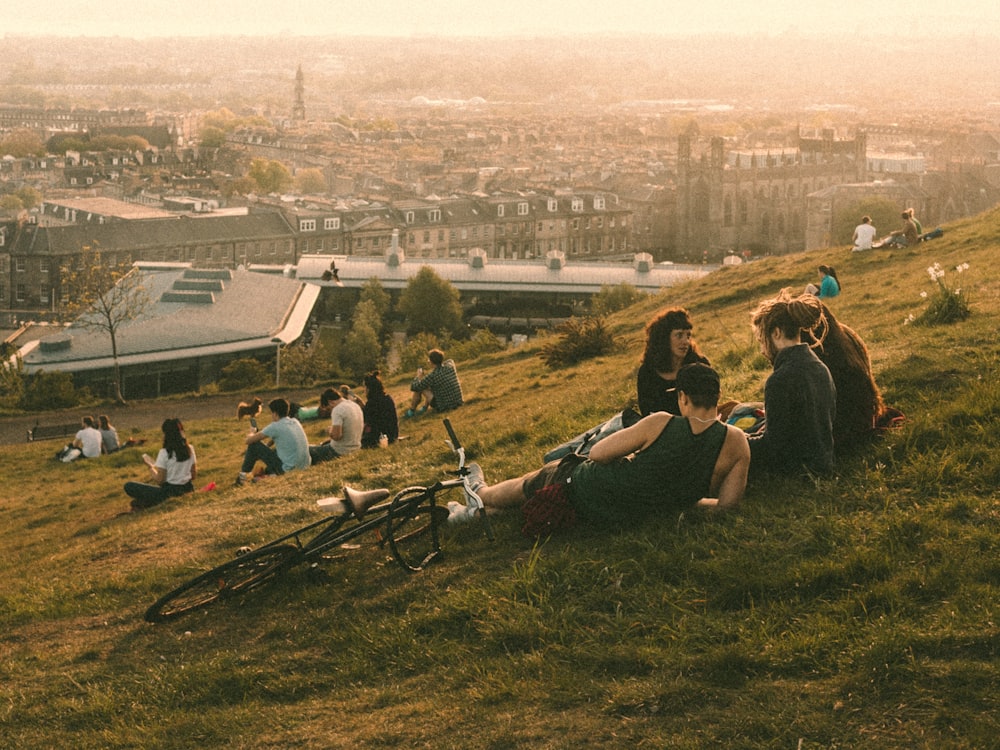 a group of people sitting on top of a lush green hillside