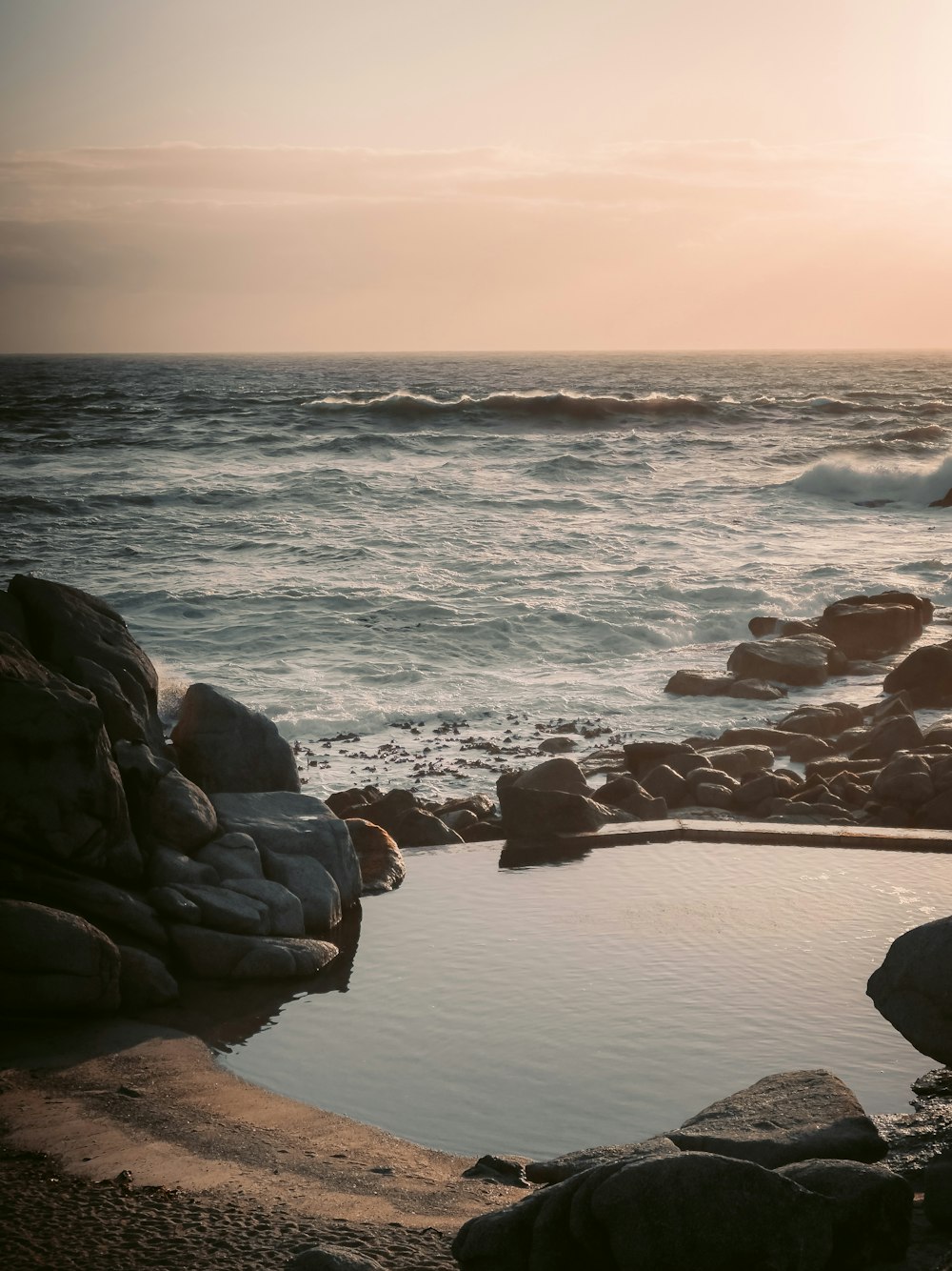 um corpo de água sentado ao lado de uma costa rochosa