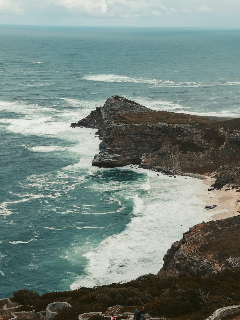 a couple of people standing on top of a cliff near the ocean