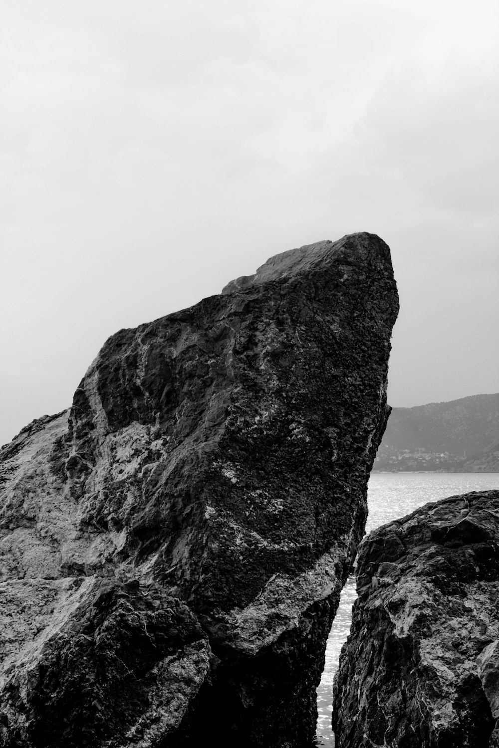a person standing on top of a large rock next to the ocean