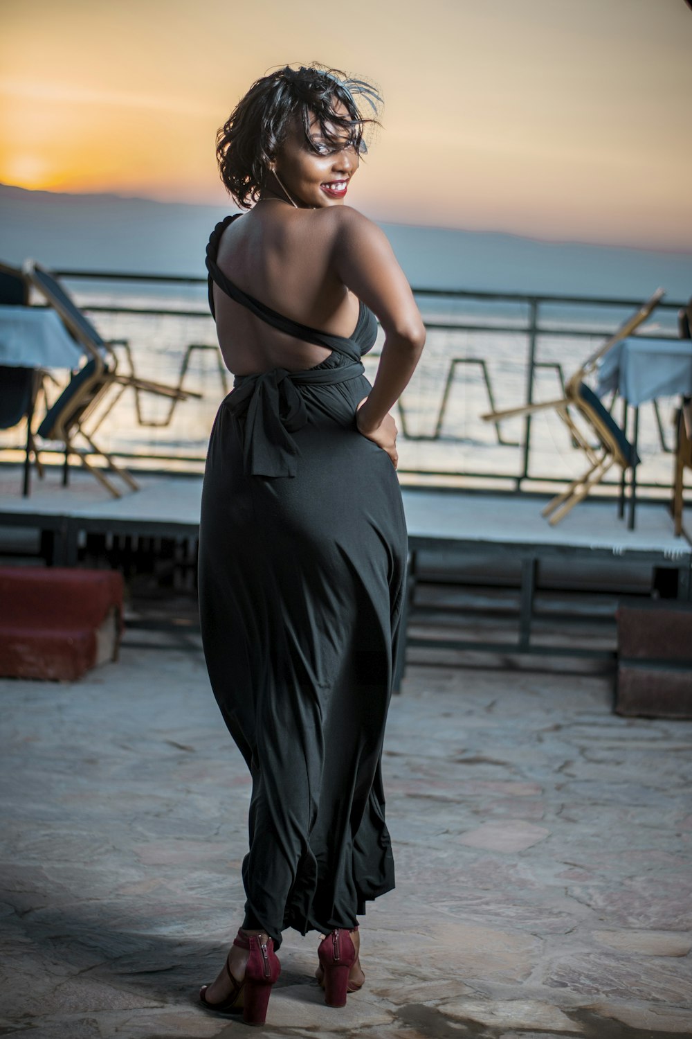 a woman in a black dress standing on a pier