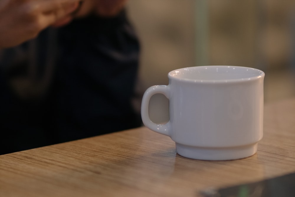 a white coffee cup sitting on top of a wooden table