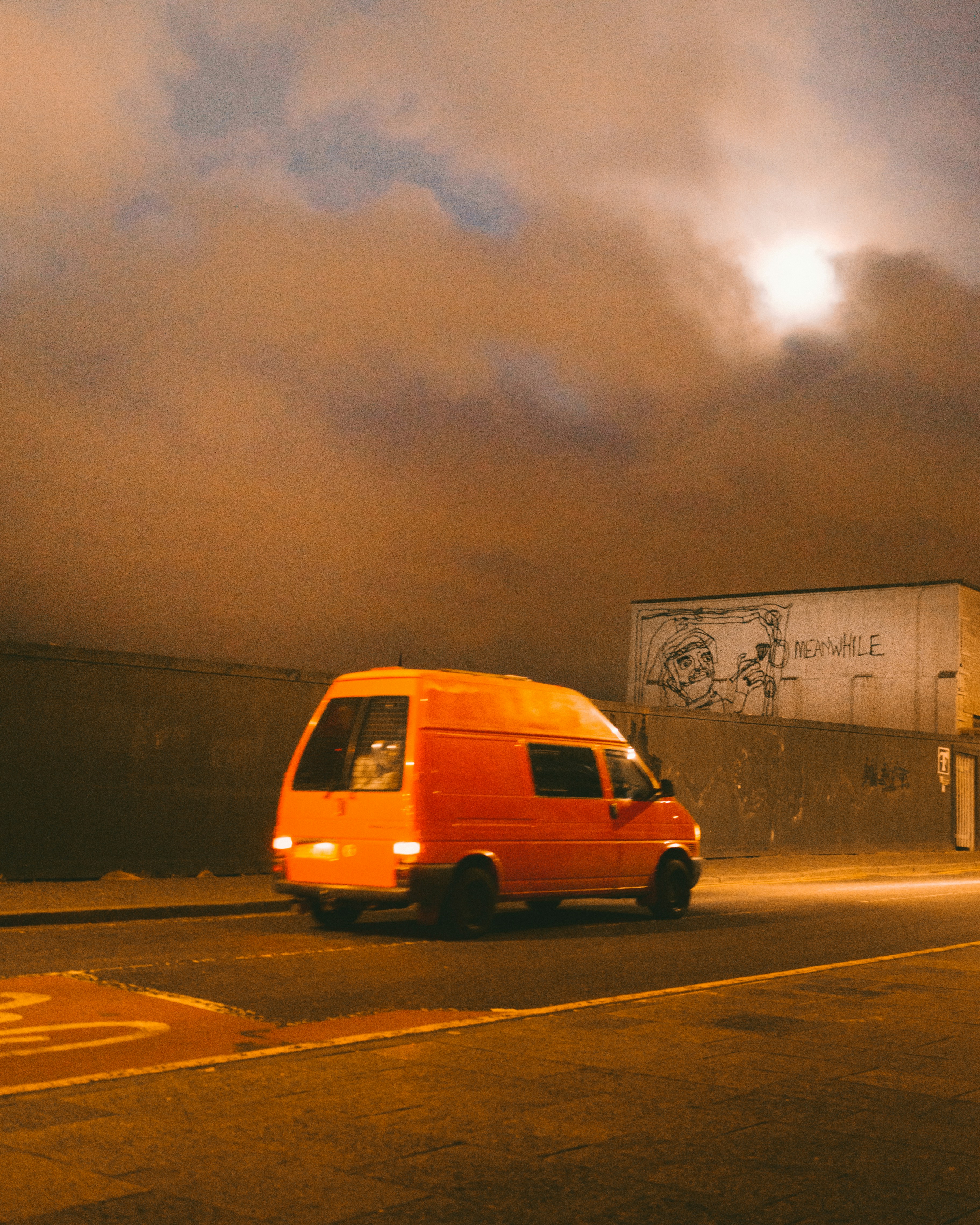 a van driving down a street under a cloudy sky