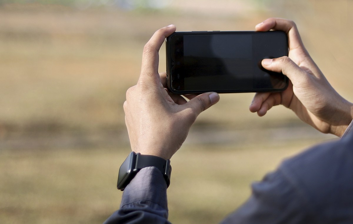 Person using a smartphone to photograph a volunteer coordination meeting with people discussing around a table