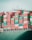 A large cargo ship is stacked high with multicolored shipping containers labeled 'Evergreen,' 'Italia,' and others. The containers are arranged in neat rows on the deck of the vessel. The structure of the ship's command tower is visible behind the containers, with various antennas and a small flag.