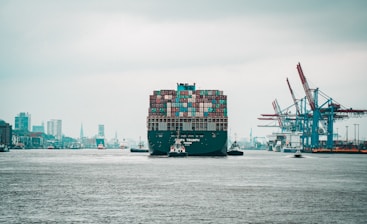 a large cargo ship in a harbor with a city in the background