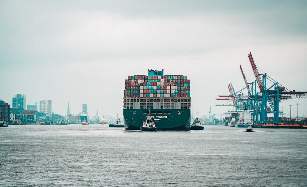 a large cargo ship in a harbor with a city in the background