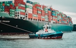 a tug boat pulling a large container ship