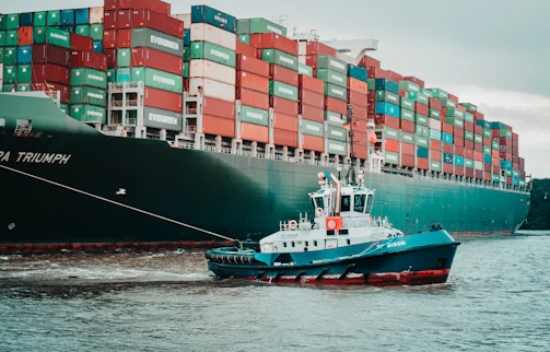 a tug boat pulling a large container ship