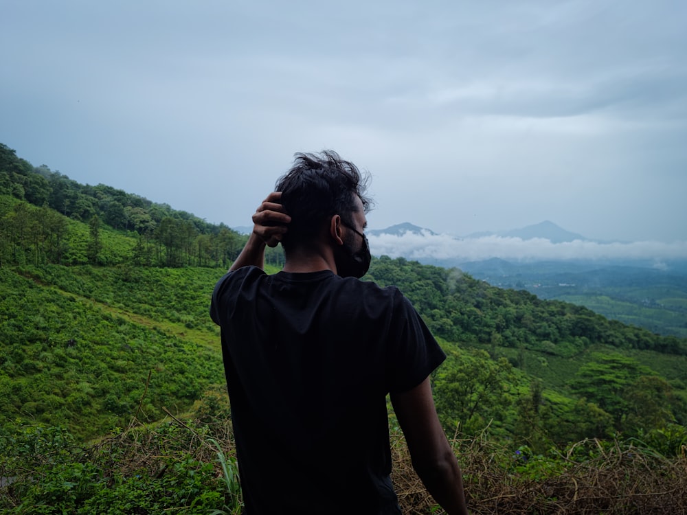 a man standing on top of a lush green hillside