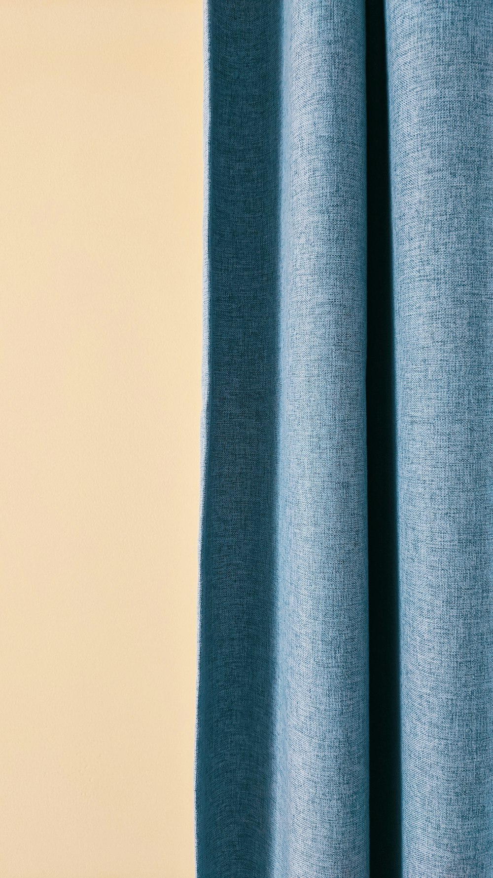 a close up of a blue curtain with a white wall in the background