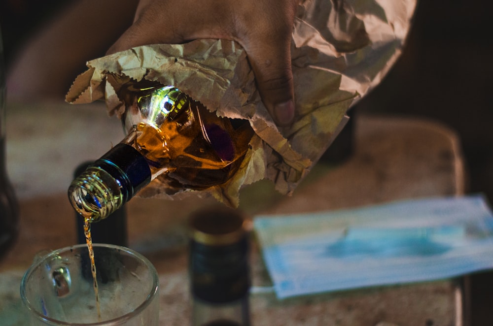 a person pouring a bottle of wine into a glass