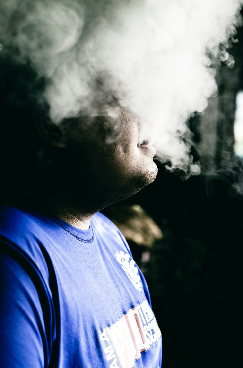 a man with a blue shirt is smoking a cigarette