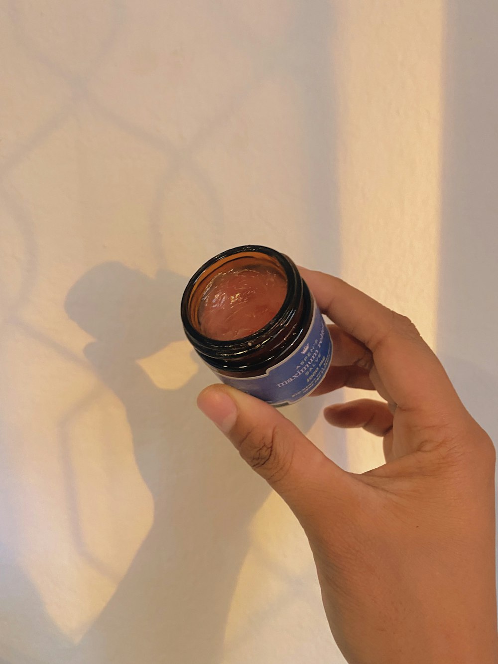a person holding a jar of makeup in their hand