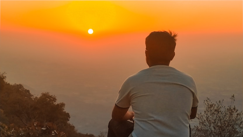A traveler gazing at a sunset over a vast landscape, symbolizing exploration and discovery.