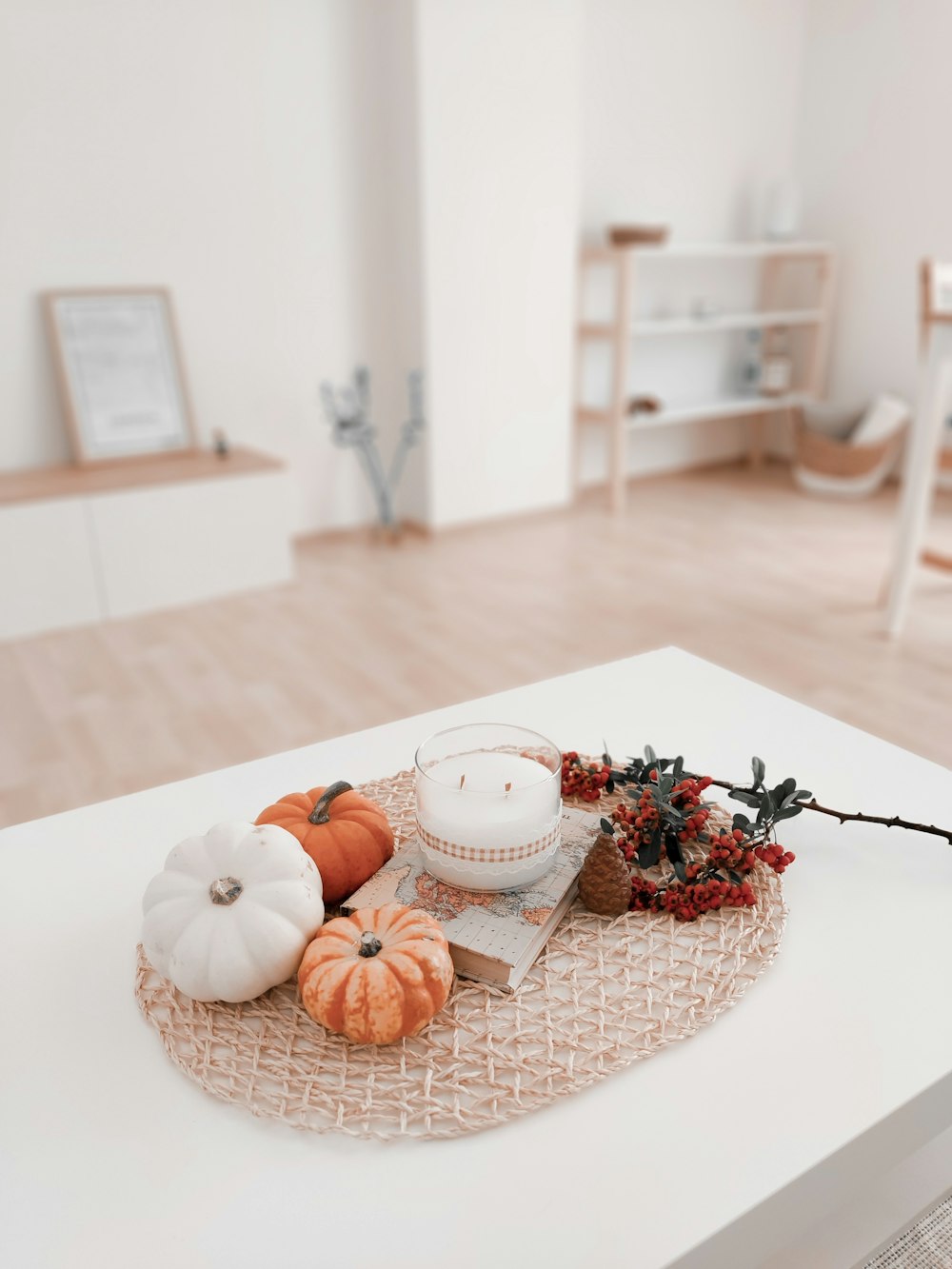 a white table topped with pumpkins and a candle