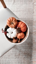 a bowl filled with fake pumpkins on top of a table